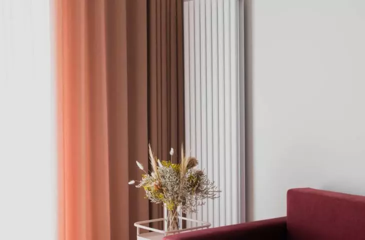 koralowa sofa i designerska lampa projektu Le Corbusiera