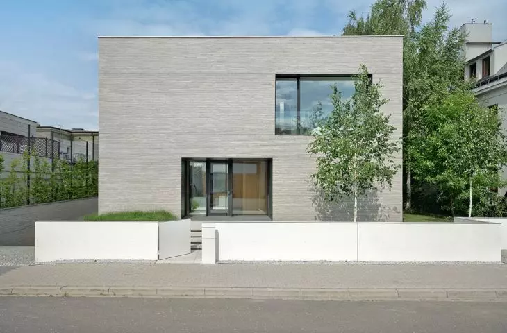 od strony ulicy widać minimalistyczną, prostą bryłę — skromną kostkę pokrytą wąskimi i podłużnymi płytkami ceramicznymi