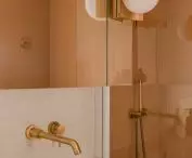 Beige tiles over the bathtub and gold faucet