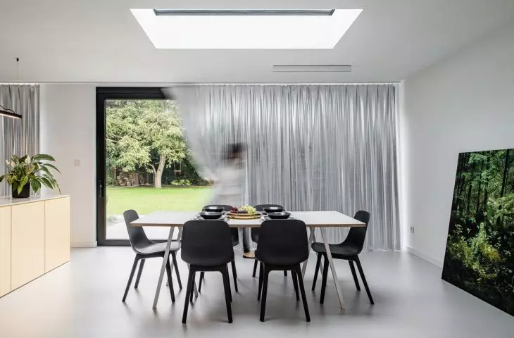 The dining table is the same size as the skylight above it