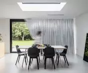 The dining table is the same size as the skylight above it