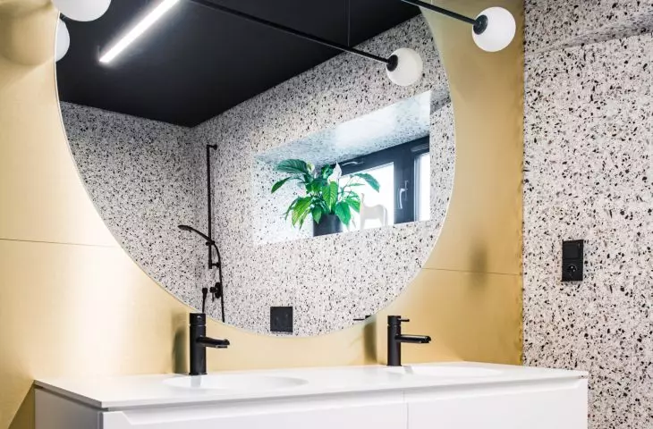 The round mirror in the bathroom has the same diameter as the decorative brick accent