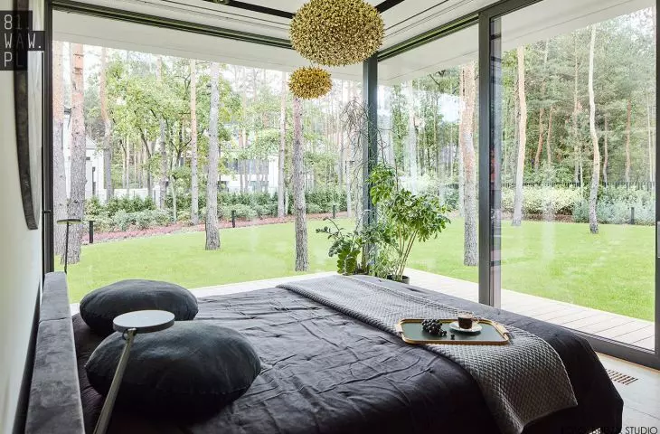dwie szklane ściany w sypialni — na wprost i z boku łóżka — dają wrażenie spania w ogrodzie