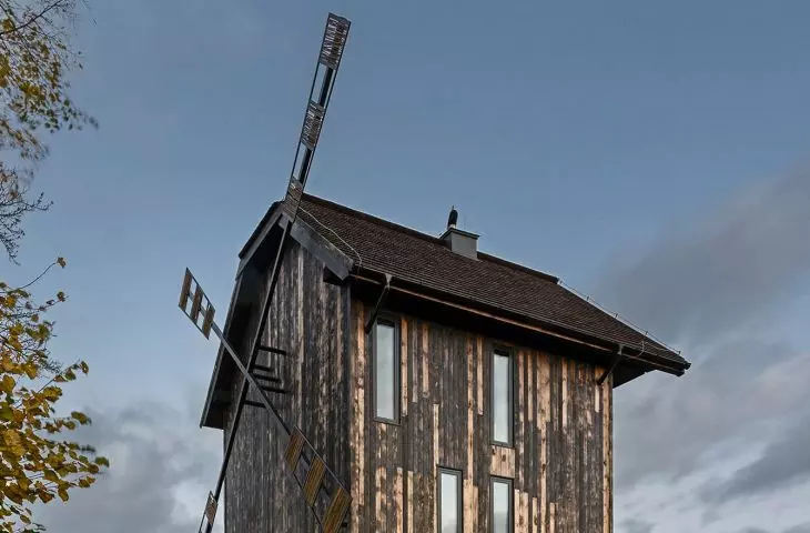 tall vertical windows in the upper parts of the house blend into the repetitive rhythm of the facade boarding
