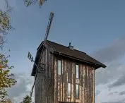 tall vertical windows in the upper parts of the house blend into the repetitive rhythm of the facade boarding