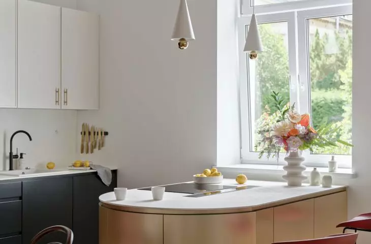 The stylish golden kitchen island is illuminated by lamps from Petite Friture brand