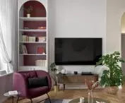 The arch in the bookcase by the TV relates to the golden arch above the entrance to the hallway