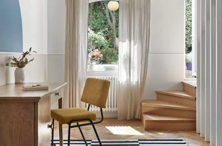 The striped pattern on the carpet in the study refers to the vertical arrangement of the slats by the stairs