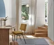 The striped pattern on the carpet in the study refers to the vertical arrangement of the slats by the stairs
