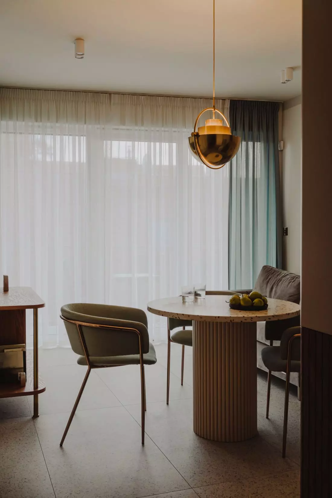 nad stołem wisi
mosiężna lampa GUBI, projekt Louisa Weisdorfa z 1972 roku