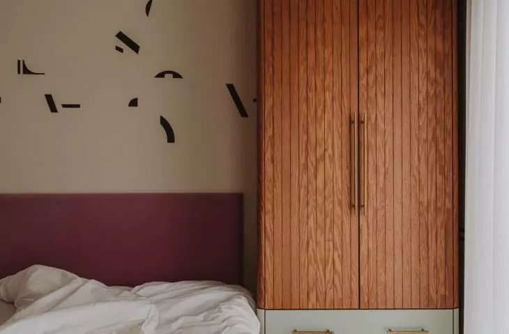 wooden closet and pink upholstered bed headboard