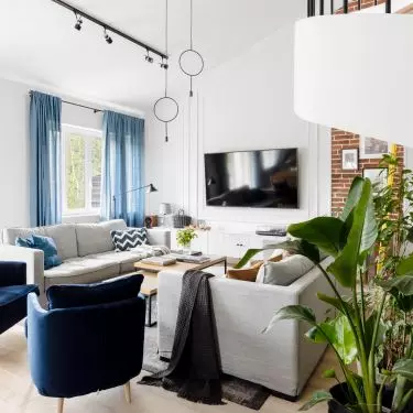 The living room, which is predominantly light in tone, has blue accents