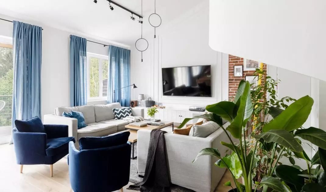 The living room, which is predominantly light in tone, has blue accents