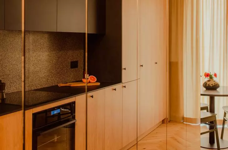 The mirrors reflect the kitchen cabinets and parquet floor