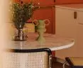 między kuchnią a salonem stoi okrągły stół otoczony designerskimi, rattanowymi krzesłami projektu Marcela Breuera
