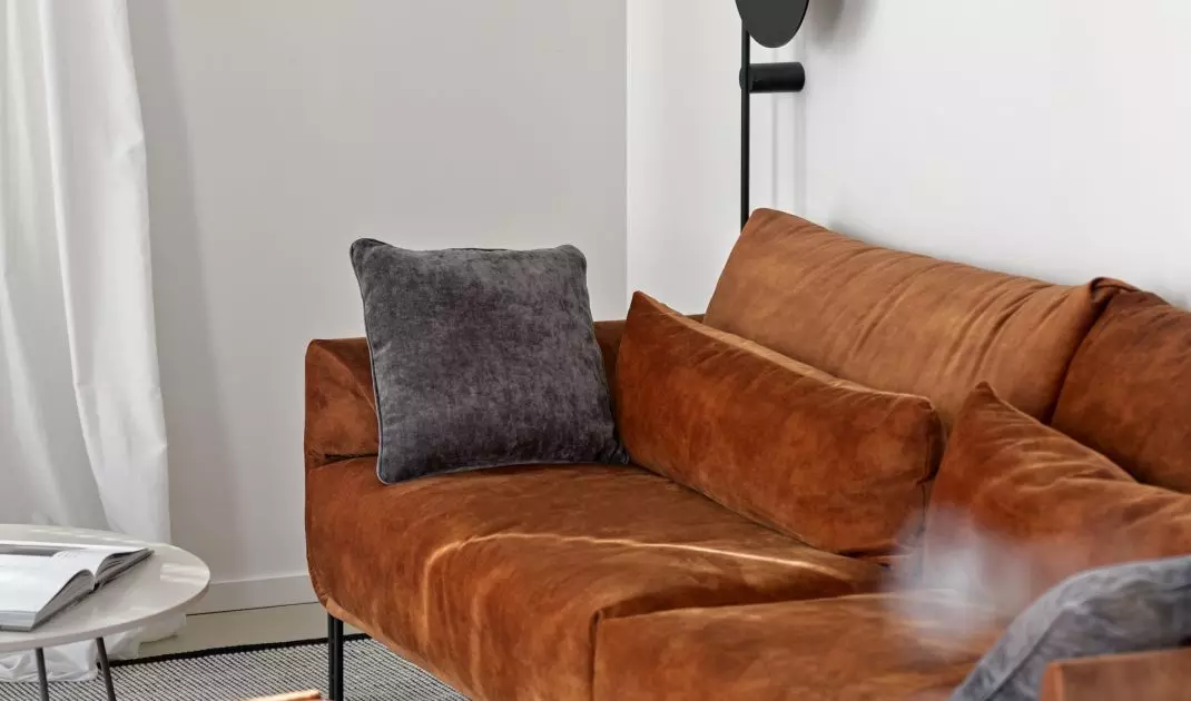 Mocnym akcentem kolorystycznym w salonie jest ruda sofa
