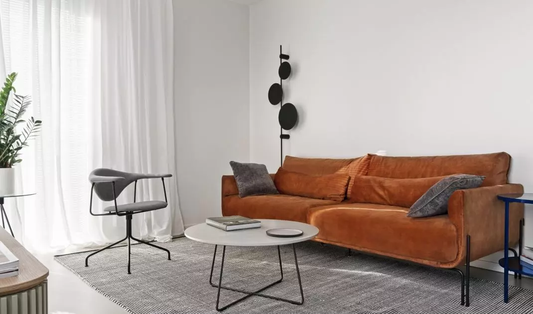 Mocnym akcentem kolorystycznym w salonie jest ruda sofa