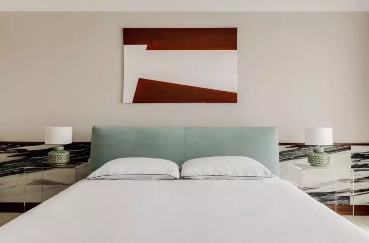 colorful accents in the bedroom include stone mirages behind the bed, a blue headrest and red in the painting