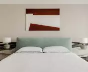 colorful accents in the bedroom include stone mirages behind the bed, a blue headrest and red in the painting