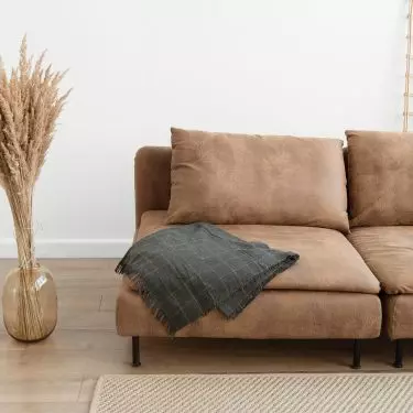 Brązowa sofa będzie wyglądać idealnie we wnętrzu w stylu boho