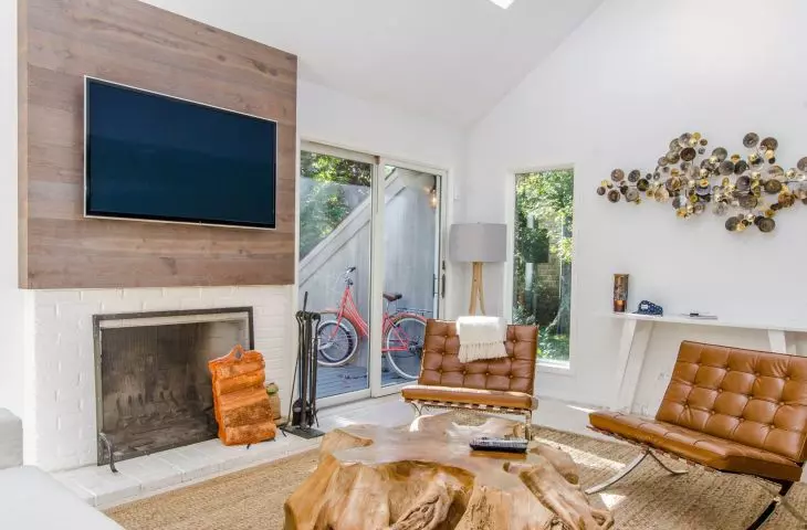 Placing the TV against a background of wood and near the fireplace will warm up the interior 