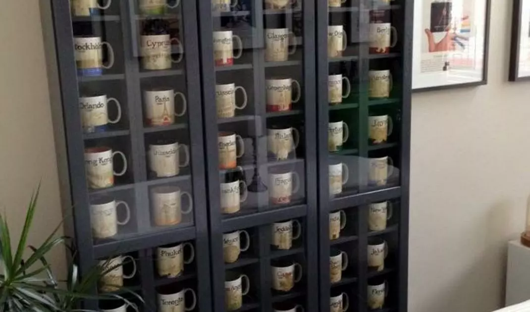 Collection of mugs in a shelf behind glass