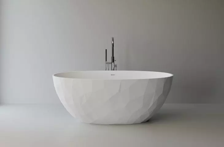 Geometryczna struktura na zewnętrznej ścianie kontrastuje z jej płynnym, owalnym wnętrzem, które zaprasza do wyjątkowych kąpieli.