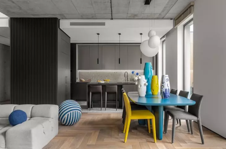 The austere interior of the living room connected to the kitchen is warmed by a wooden floor