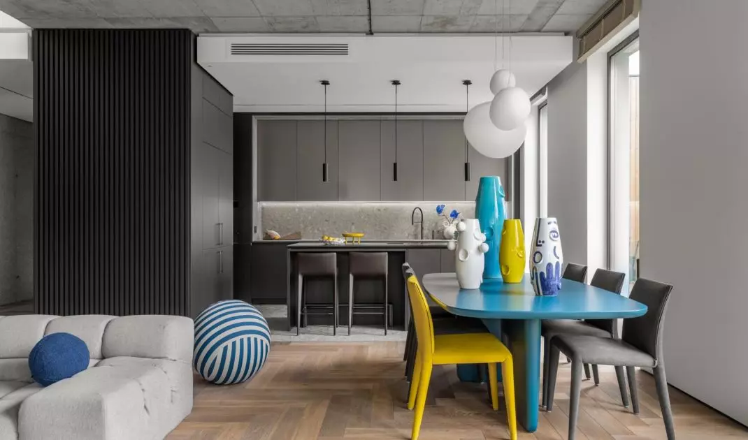 The austere interior of the living room connected to the kitchen is warmed by a wooden floor