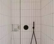 shower cubicle lined with vertical white tiles