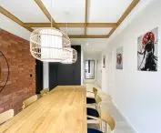 The dining room has a long table and the walls are decorated with graphics