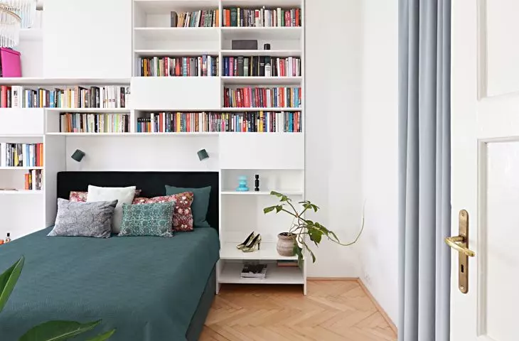 the wall behind the bed is built in with a system of shelves and cabinets