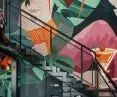 Schody prowadzące na antresole obok których zdecydowano się na mural