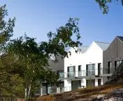 The facade is made of tan wood and white plaster