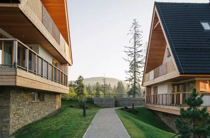 Roofs are covered with black-colored tile roofing imitating shingles, and stone foundations of broken sandstone cut off the first floor