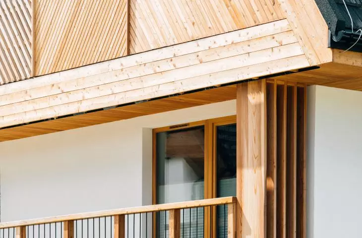 Walls covered with plaster in a shade of warm white correspond with wooden elements of the facade
